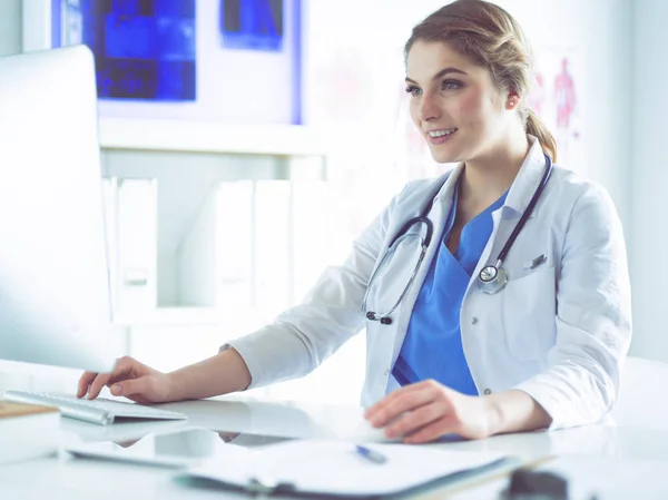 Doctora joven sentada en un escritorio y trabajando en la computadora en la oficina del hospital. Atención médica, seguro y concepto de ayuda. Médico listo para examinar al paciente —  Fotos de Stock