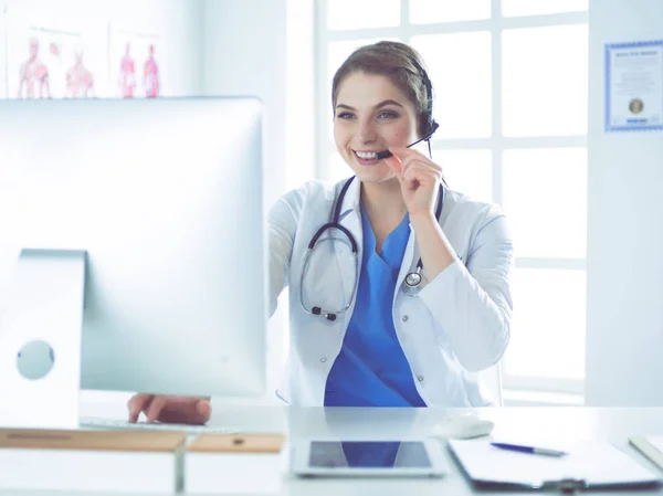 Young practitioner doctor working at the clinic reception desk, she is answering phone calls and scheduling appointments — Stock Photo, Image