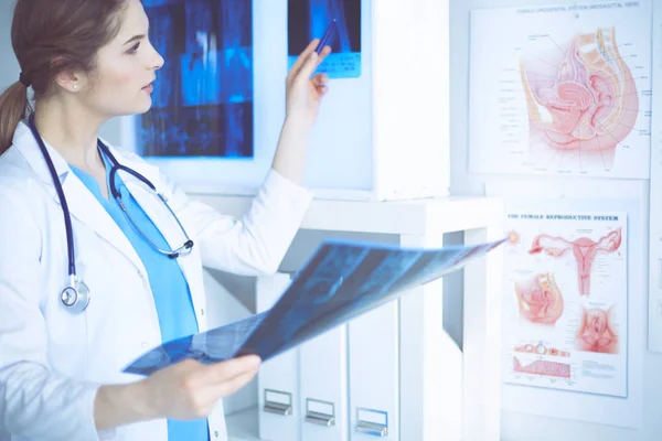 Young female doctor looking at the x-ray picture of lungs in hospital — Stock Photo, Image
