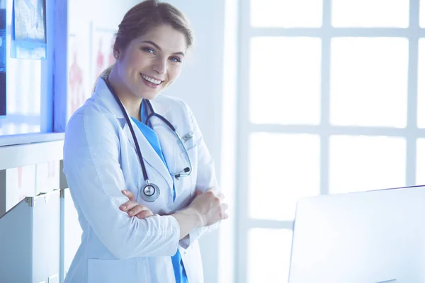 Mujer joven médica en uniforme blanco de pie en la oficina de clínicas —  Fotos de Stock