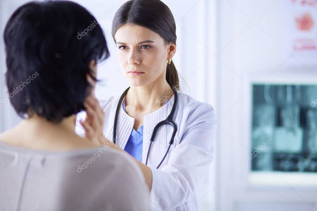 A serious female doctor examining a patients lymph nodes