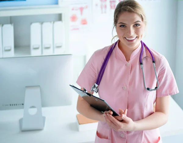 Sorridente medico donna con una cartella in uniforme in piedi in ospedale — Foto Stock