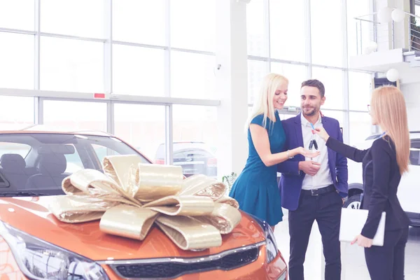 Mooie vrolijke vrouw die autosleutels vasthoudt, haar man omarmt na het kopen van nieuwe auto — Stockfoto