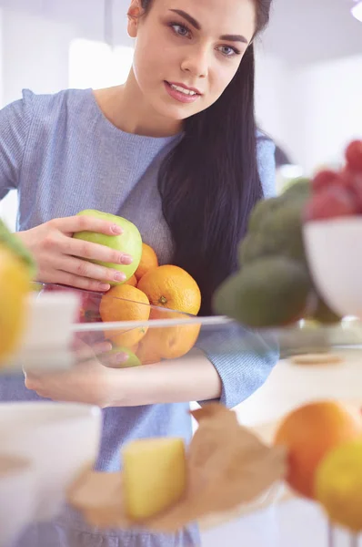 Mosolygó nő vesz egy friss gyümölcsöt ki a hűtőből, egészséges étel koncepció — Stock Fotó