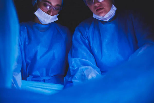 Oříznutý obrázek skalpelu s lékaři provádějícími operaci. — Stock fotografie