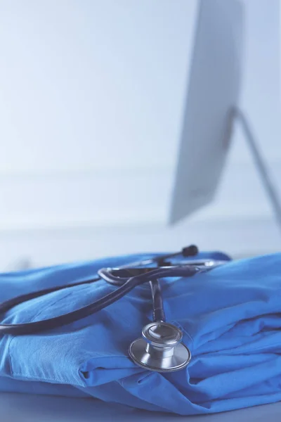 Wizerunek stetoskopu i płaszcza lekarskiego na stole w pokoju konsultacyjnym. Koncepcja medyczna — Zdjęcie stockowe