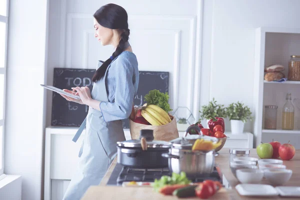 Beautiful young woman using a digital tablet in the kitchen — Stock Photo, Image