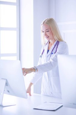 Hastane ofisindeki bilgisayara işaret ederken iş yerindeki genç kadın doktor.