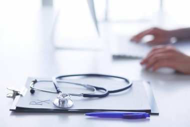 Stetoskop yakın plan dizüstü bilgisayarda yazan kadın doktorun yanında duruyor.