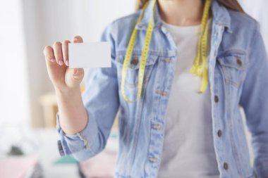 Genç bir kadın elinde boş beyaz kartvizit tutuyor.