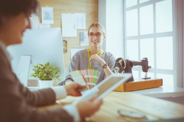 Kadın terzi, dikiş atölyesindeki özel dikim elbise hakkında potansiyel müşteriyle iletişim kuruyor.