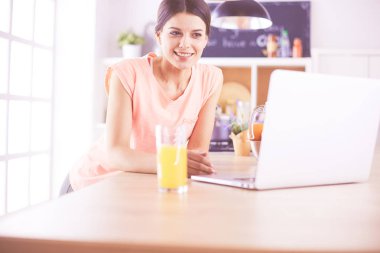 Mutfakta dizüstü bilgisayara benzeyen tariflerle gülümseyen genç bir kadın. Gıda blogcusu kavramı