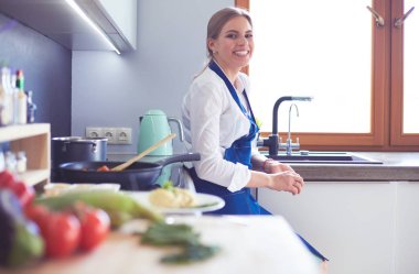 Mutfakta sobanın yanında duran genç bir kadın.