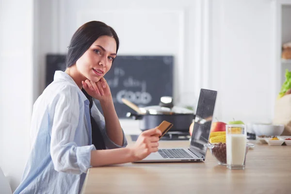 Lachende vrouw online winkelen met behulp van Tablet PC- en creditcard in keuken — Stockfoto