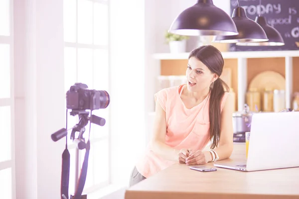 Ung kvinna i köket med bärbar dator ser recept, leende. Begreppet livsmedelsbloggare — Stockfoto