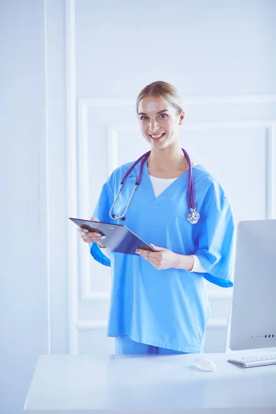 Médecin souriante avec un dossier en uniforme debout — Photo