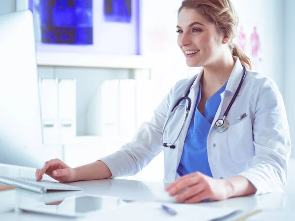 Jeune femme médecin assise à un bureau et travaillant sur l'ordinateur au bureau de l'hôpital. Soins de santé, assurance et concept d'aide. Médecin prêt à examiner le patient — Photo