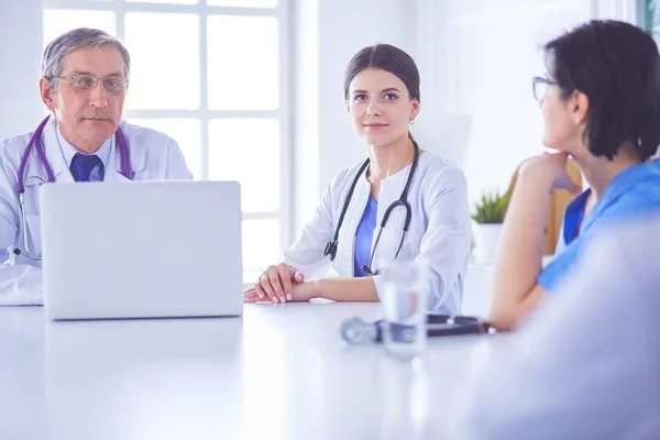 Serieuze medische team met behulp van een laptop in een heldere consulting room — Stockfoto