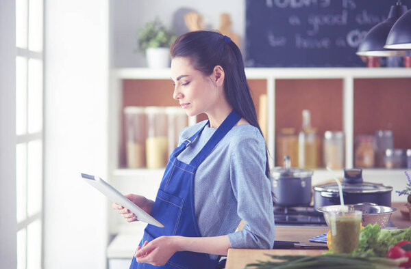 Young woman using a tablet computer to cook in her kitchen