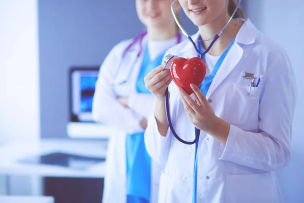 Abgeschnittene Aufnahme zweier junger Ärztinnen mit Stethoskop am Herzen. — Stockfoto