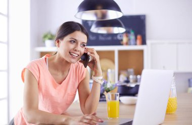 Mutfakta dizüstü bilgisayara benzeyen tariflerle gülümseyen genç bir kadın. Gıda blogcusu kavramı