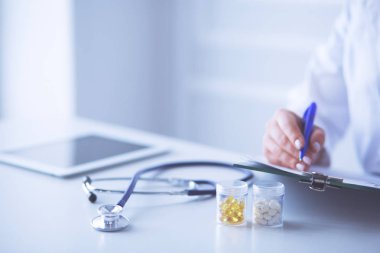 Steteskop cam masanın üzerinde duruyor. Yoğun bir doktor geçmişinde dizüstü bilgisayarı var. İlaç ya da eczane konsepti. Doktor çalışma masasında tıbbi aletler