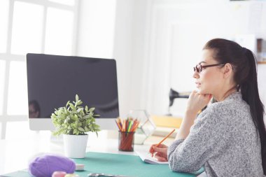 Moda tasarımcıları stüdyoda çalışıyor. Masanın üzerinde oturuyorlar..