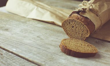 Dilimlenmiş ekmek somunu tahtadan masanın üzerinde kağıda sarılmış.