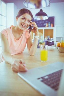 Mutfakta dizüstü bilgisayara benzeyen tariflerle gülümseyen genç bir kadın. Gıda blogcusu kavramı