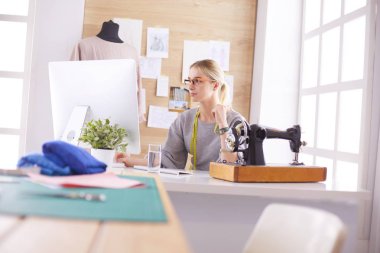 Masasında dikiş makinesi olan bir fabrikada genç ve güzel bir kız.