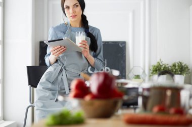 Tablette tarifi takip eden bir kadın evde yemek pişiriyor.