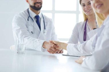 Doktor ofiste erkek bir hastayla el sıkışıyor.