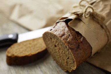 Tahta masanın üzerinde kağıda sarılı bir somun ekmek.