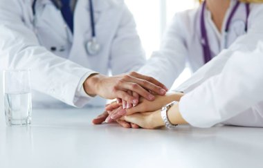 Doktorlar el ele tutuşup yakın çekim yapıyor.
