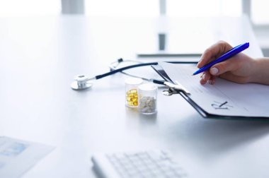 Kadınların elleri bir kağıt parçasına yazı yazıp masasında kalem bırakırlar.