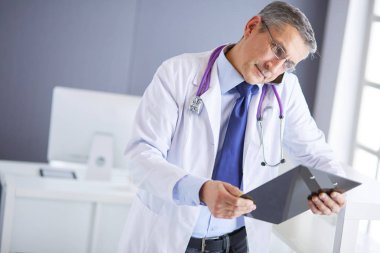 Erkek doktor hastanedeki panoya notlar yazıyor.