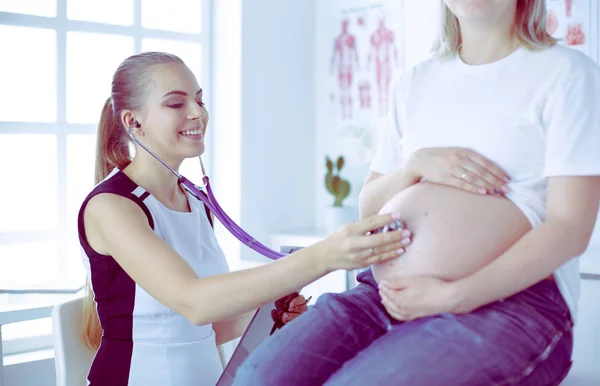 Giovane medico donna esaminando donna incinta presso la clinica. — Foto Stock