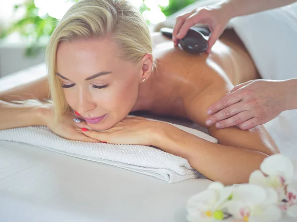 Mladá žena dostává masáž lávovými kameny ve spa salonu. krása Ošetřovatelský koncept — Stock fotografie