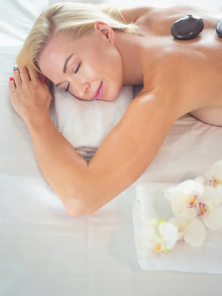 Krásná mladá žena s očima uzavřen příjem masáž lávovými kameny v salonu spa. — Stock fotografie