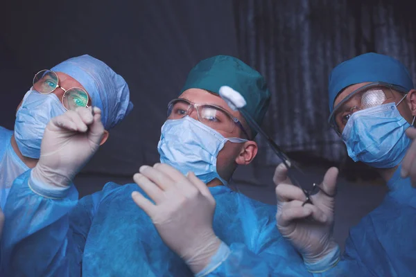 Grupo de cirurgiões no trabalho em sala de operações tonificada em azul. Equipe médica realizando operação — Fotografia de Stock