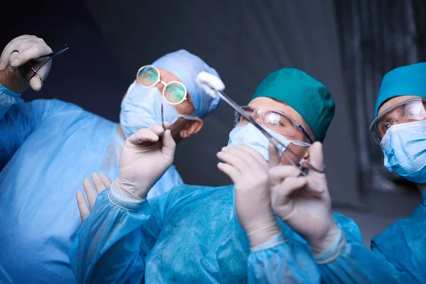 Skupina chirurgů, kteří pracovali na operačním sále, modrým tónem. Lékařský tým provádí operaci — Stock fotografie