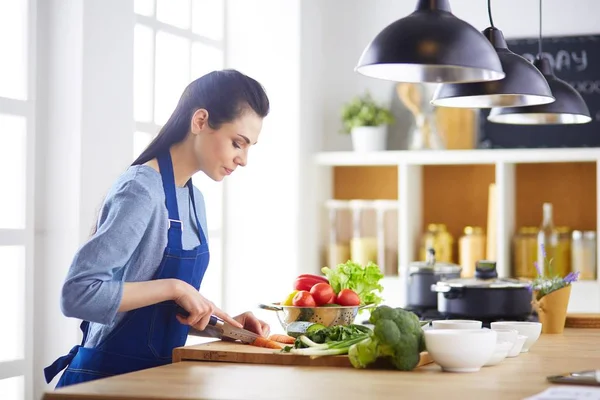 Jovem mulher cortando legumes na cozinha em casa — Fotografia de Stock