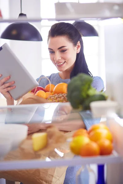 Donna sorridente che prende una frutta fresca dal frigorifero, concetto di cibo sano — Foto Stock