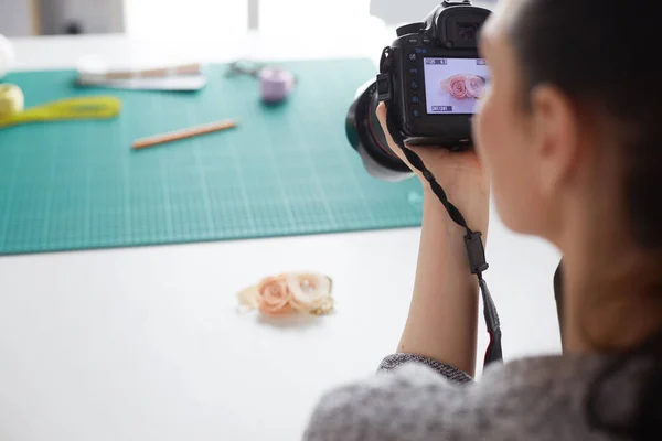 Jonge vrouw ontwerper staat in de buurt van de werkplek en fotograferen op digitale camera — Stockfoto