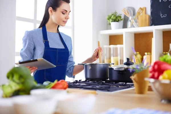 Mujer joven usando una tableta para cocinar en su cocina — Foto de Stock