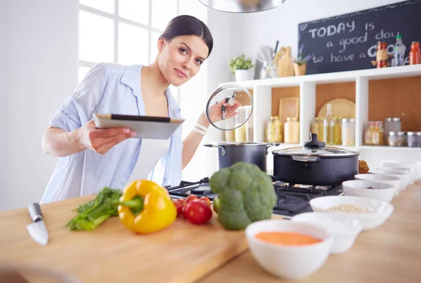 Junge Frau steht am Herd in der Küche — Stockfoto