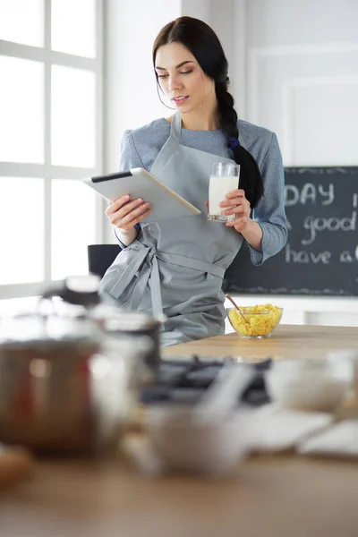 Woman baking at home following recipe on a tablet — Stock Photo, Image