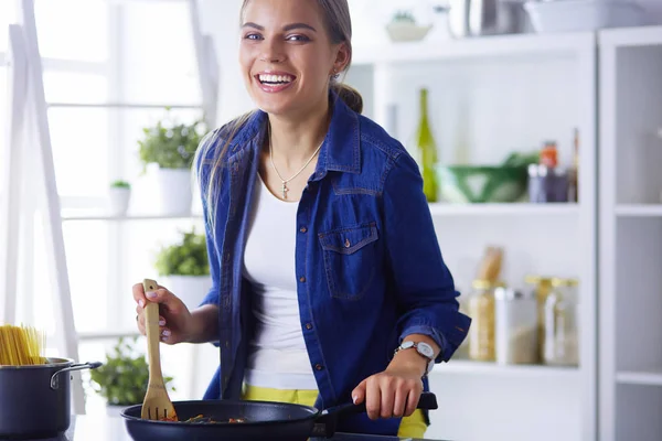 Mujer joven en la cocina preparando una comida — Foto de Stock