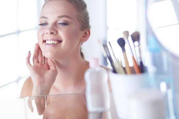 Giovane donna in accappatoio guardando nello specchio del bagno — Foto Stock