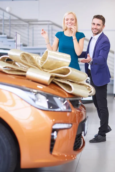 Muž dává dárek - auto své ženě. To ji překvapuje. Mají z toho velkou radost. — Stock fotografie